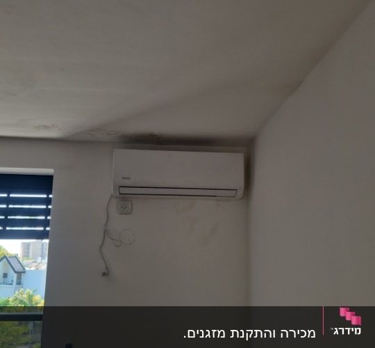 מזגן מותקן על קיר בחדר עם חלון